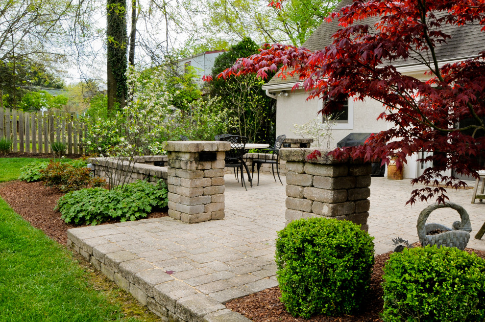 Cette image montre un grand jardin arrière traditionnel avec un mur de soutènement, une exposition ensoleillée et des pavés en béton.