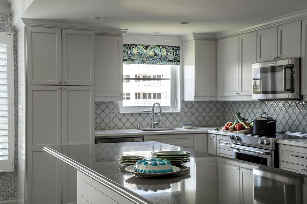 Mid-sized transitional u-shaped eat-in kitchen photo in Miami with an undermount sink, recessed-panel cabinets, white cabinets, quartz countertops, white backsplash, ceramic backsplash, stainless steel appliances, an island and white countertops