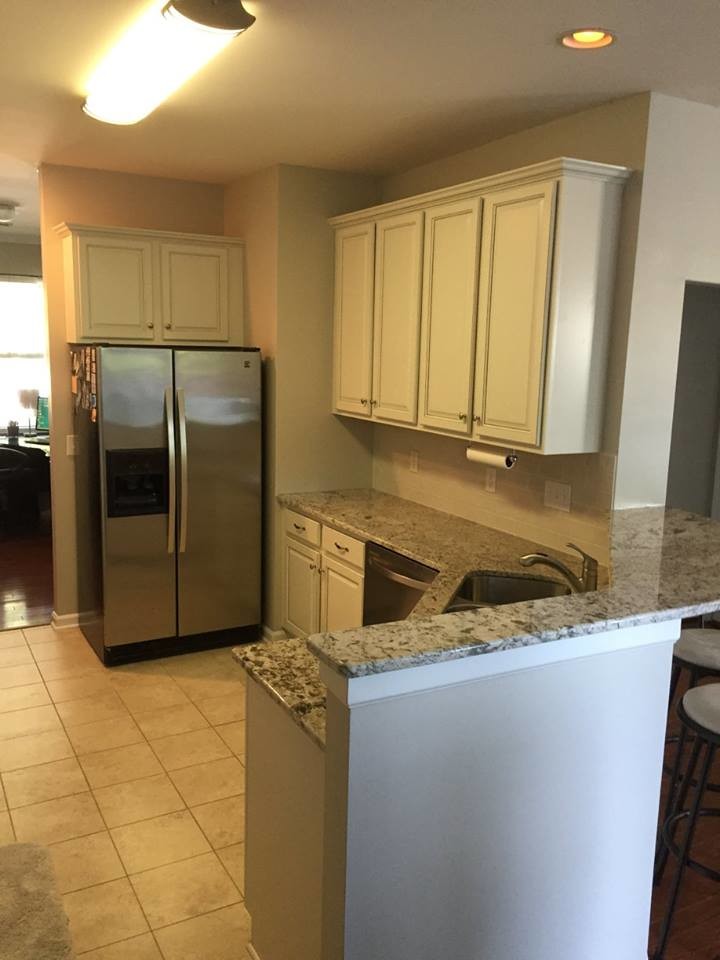 Mid-sized transitional u-shaped ceramic tile home design photo in Charlotte with an undermount sink, raised-panel cabinets, white cabinets, granite countertops, white backsplash, subway tile backsplash, stainless steel appliances and no island