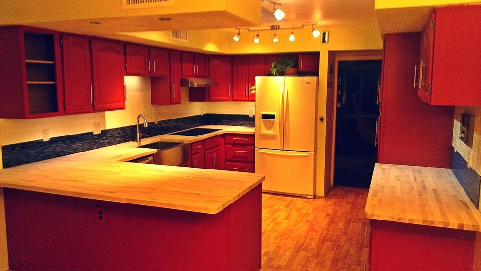 Example of a mid-sized mountain style l-shaped light wood floor eat-in kitchen design in Phoenix with a farmhouse sink, raised-panel cabinets, medium tone wood cabinets, wood countertops, black backsplash, matchstick tile backsplash, white appliances and a peninsula