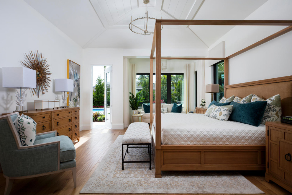 Inspiration for a large beach style master bedroom in Miami with white walls, medium hardwood floors and brown floor.