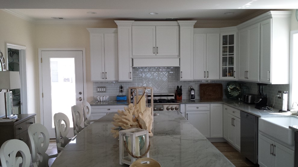 Eat-in kitchen - large coastal u-shaped medium tone wood floor eat-in kitchen idea in New York with a farmhouse sink, recessed-panel cabinets, white cabinets, quartzite countertops, stainless steel appliances and an island