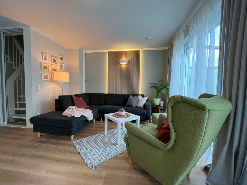 Cette photo montre un très grand salon ouvert avec un mur vert, un sol en bois brun et du lambris.