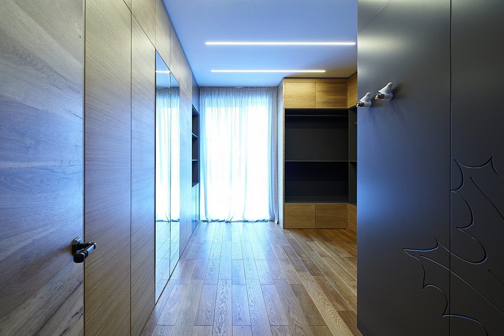 Modern inredning av ett stort walk-in-closet för könsneutrala, med skåp i mellenmörkt trä, laminatgolv och beiget golv
