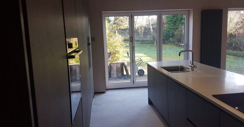 Inspiration for a contemporary eat-in kitchen in West Midlands with an integrated sink, flat-panel cabinets, solid surface benchtops, with island and white benchtop.