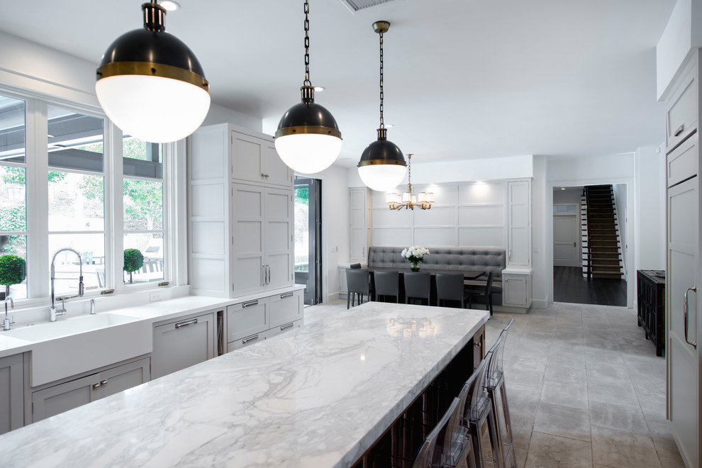 This is an example of an expansive transitional u-shaped eat-in kitchen in Los Angeles with a farmhouse sink, beaded inset cabinets, grey cabinets, marble benchtops, white splashback, marble splashback, stainless steel appliances, limestone floors, with island, beige floor and white benchtop.