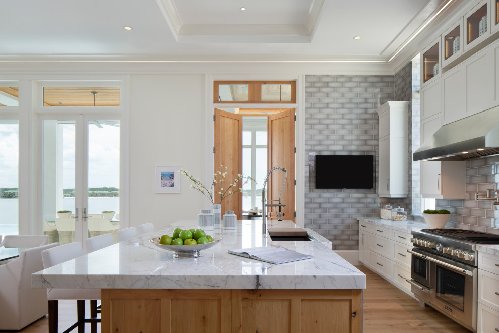 Inspiration for a huge transitional l-shaped medium tone wood floor and beige floor open concept kitchen remodel in Miami with an undermount sink, shaker cabinets, white cabinets, gray backsplash, stainless steel appliances, an island and white countertops