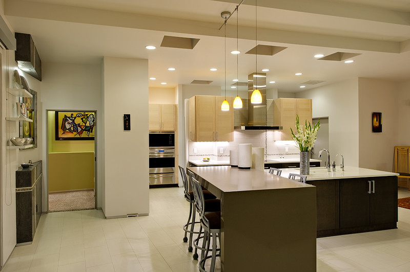 This is an example of a large modern l-shaped eat-in kitchen in Albuquerque with an undermount sink, flat-panel cabinets, light wood cabinets, white splashback, stainless steel appliances, ceramic floors, with island, solid surface benchtops and porcelain splashback.