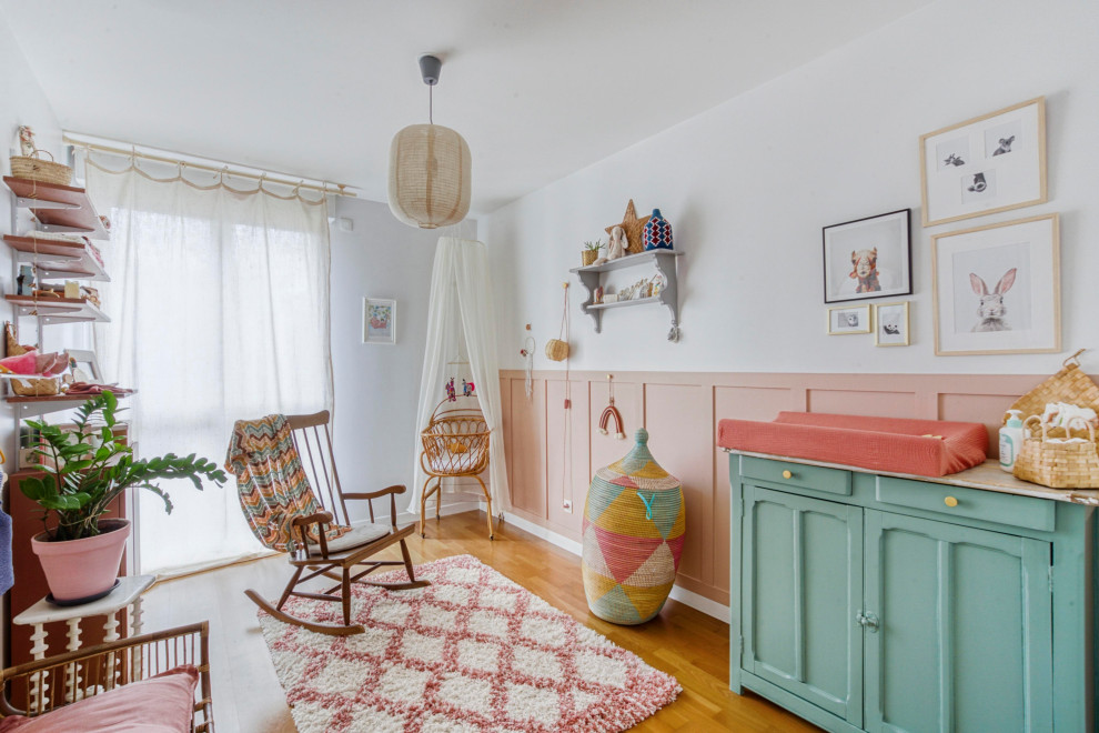 Diseño de habitación de bebé niña ecléctica de tamaño medio con paredes rosas, suelo de madera en tonos medios y suelo marrón
