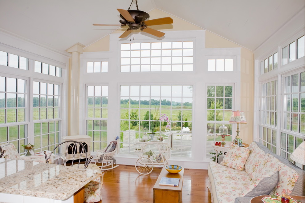 This is an example of a country sunroom in Other with medium hardwood floors and a wood stove.