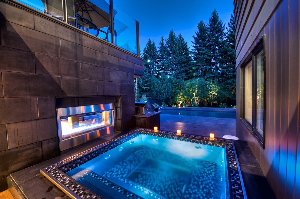 This is an example of a small contemporary backyard rectangular aboveground pool in Calgary with a hot tub and concrete pavers.