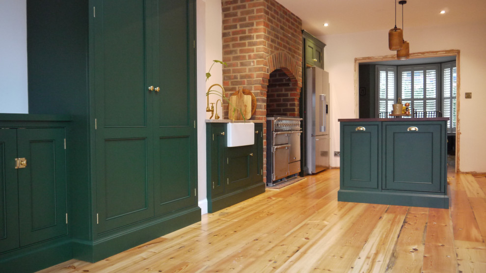 Zweizeilige, Mittelgroße Klassische Wohnküche mit Landhausspüle, Schrankfronten im Shaker-Stil, grünen Schränken, Arbeitsplatte aus Holz, hellem Holzboden, Kücheninsel, braunem Boden und brauner Arbeitsplatte in London