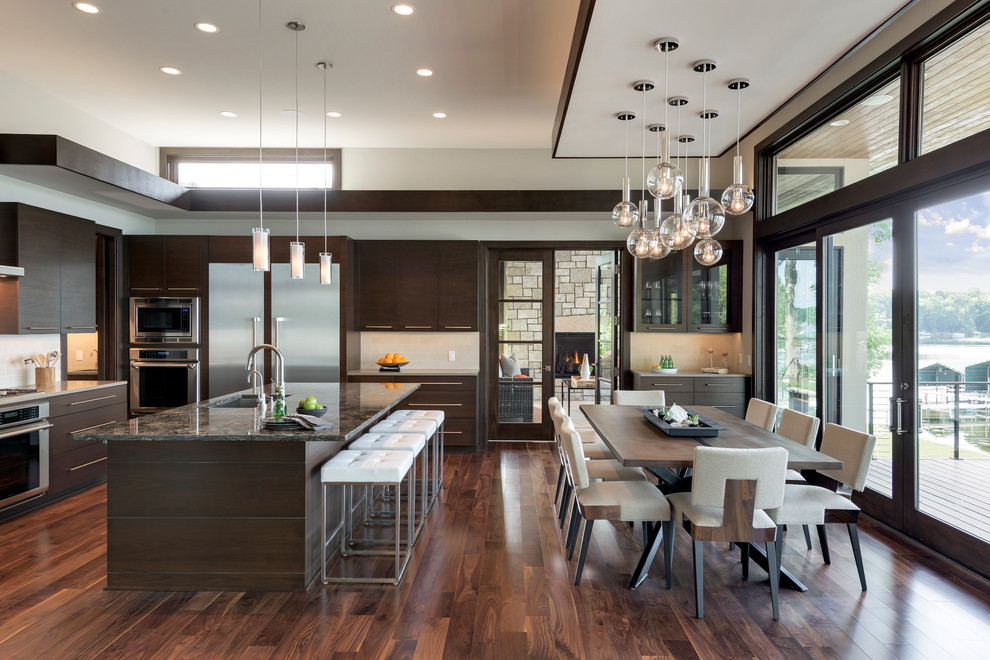 Expansive contemporary open plan kitchen in Minneapolis with an undermount sink, flat-panel cabinets, dark wood cabinets, granite benchtops, beige splashback, stainless steel appliances, with island and dark hardwood floors.