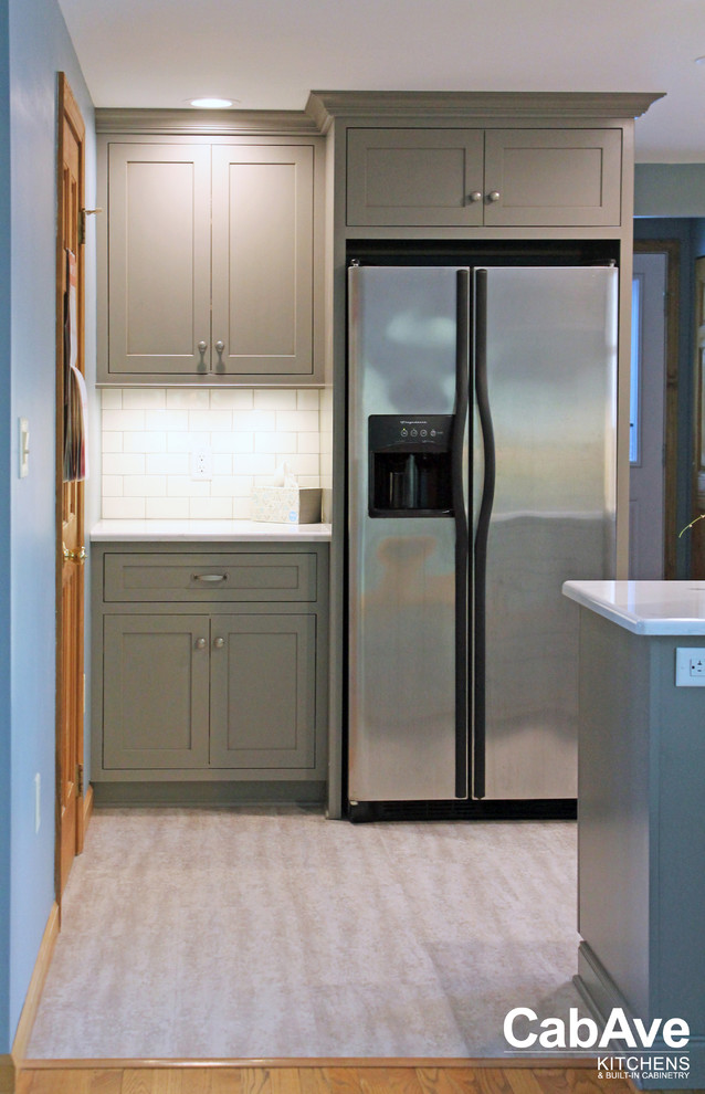 Inspiration for a small transitional l-shaped laminate floor and gray floor enclosed kitchen remodel with a farmhouse sink, recessed-panel cabinets, gray cabinets, quartz countertops, white backsplash, subway tile backsplash, stainless steel appliances and a peninsula