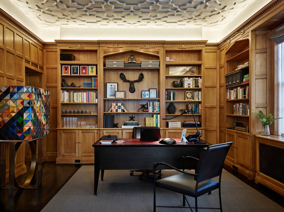 Traditional study room in London with brown walls, dark hardwood floors and a freestanding desk.