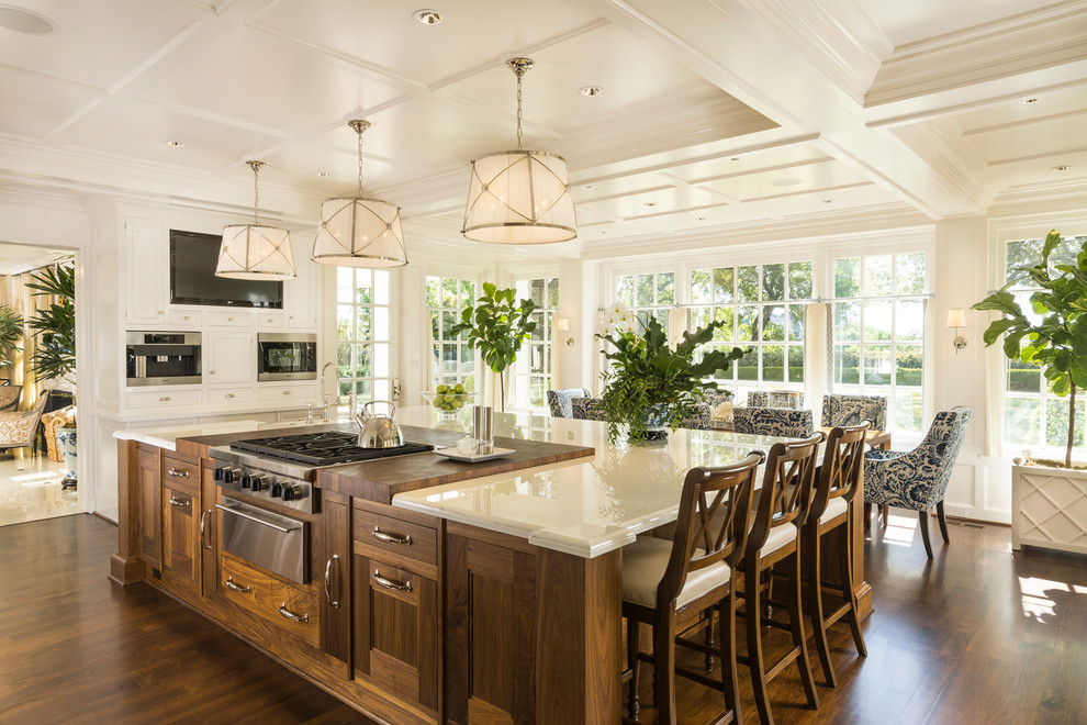 Inspiration for a traditional eat-in kitchen in Dallas with recessed-panel cabinets, dark wood cabinets, stainless steel appliances, dark hardwood floors and with island.