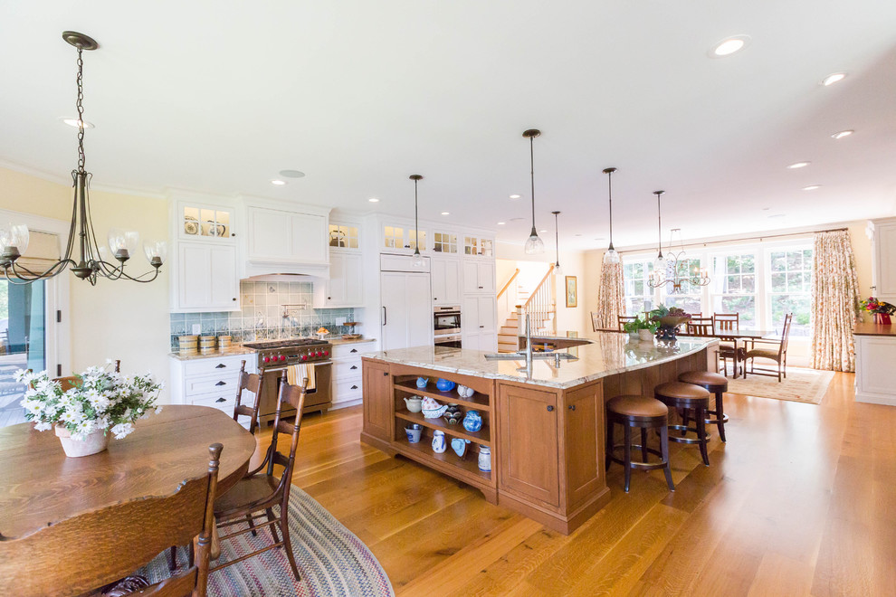 Expansive arts and crafts u-shaped eat-in kitchen in New York with an undermount sink, recessed-panel cabinets, white cabinets, granite benchtops, blue splashback, ceramic splashback, panelled appliances, medium hardwood floors and with island.