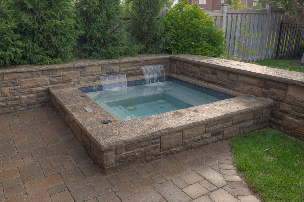 Design ideas for a large traditional backyard pool in Other with brick pavers and a hot tub.
