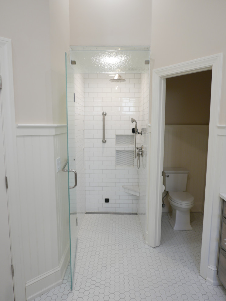 This is an example of a large classic ensuite bathroom in Other with raised-panel cabinets, medium wood cabinets, a freestanding bath, a built-in shower, a two-piece toilet, white tiles, ceramic tiles, beige walls, porcelain flooring, a submerged sink, engineered stone worktops, white floors, a hinged door, white worktops, a wall niche, a single sink, a built in vanity unit, a vaulted ceiling and wainscoting.