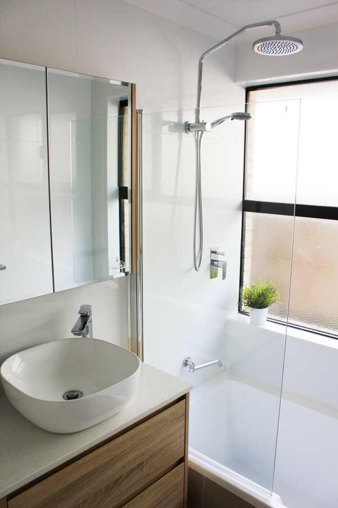 Mid-sized modern 3/4 bathroom in Perth with flat-panel cabinets, beige cabinets, a drop-in tub, a shower/bathtub combo, a one-piece toilet, white tile, ceramic tile, white walls, porcelain floors, a vessel sink, solid surface benchtops, beige floor, a hinged shower door and white benchtops.