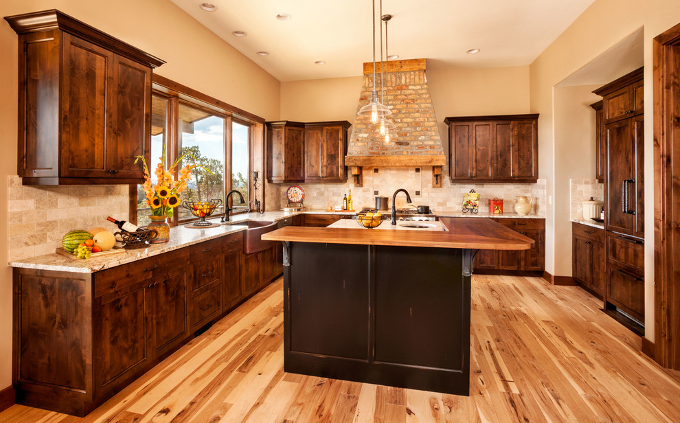 Large country u-shaped eat-in kitchen in Other with an undermount sink, recessed-panel cabinets, dark wood cabinets, quartzite benchtops, beige splashback, travertine splashback, panelled appliances, light hardwood floors, with island, brown floor and beige benchtop.