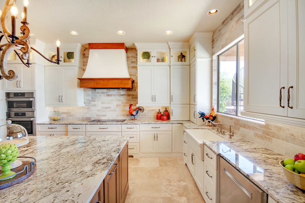 Open concept kitchen - large transitional u-shaped travertine floor and beige floor open concept kitchen idea in Phoenix with recessed-panel cabinets, white cabinets, granite countertops, an island, multicolored countertops, a farmhouse sink, gray backsplash, porcelain backsplash and stainless steel appliances