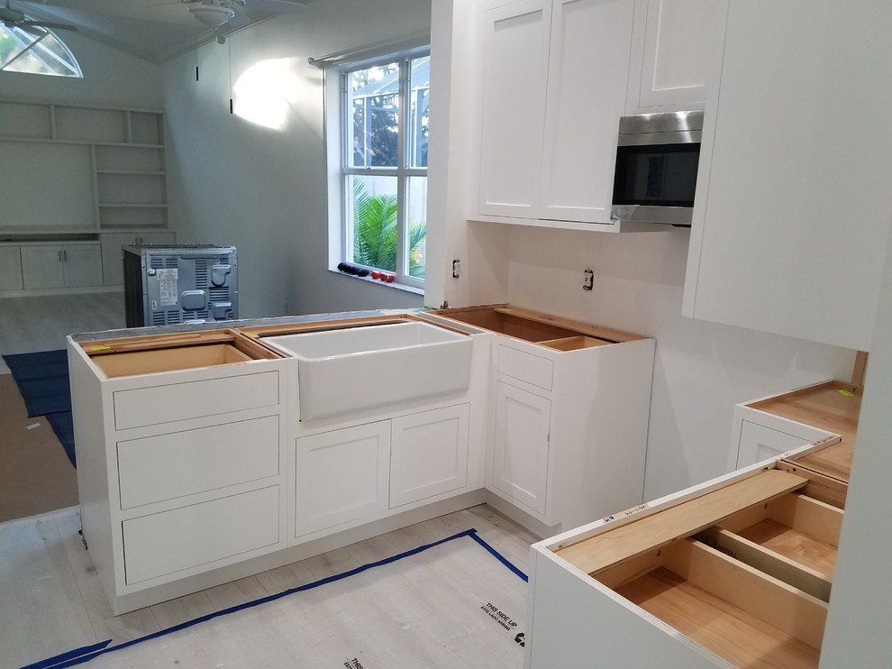 Kitchen - mid-sized transitional u-shaped laminate floor and white floor kitchen idea in Miami with a farmhouse sink, flat-panel cabinets, white cabinets, marble countertops, white backsplash, cement tile backsplash, stainless steel appliances, an island and white countertops