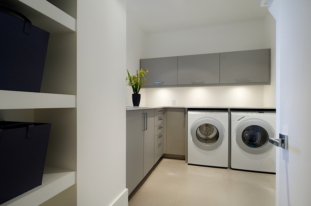 This is an example of a contemporary laundry room in Calgary with an undermount sink, flat-panel cabinets, grey cabinets, quartz benchtops, ceramic floors and a side-by-side washer and dryer.