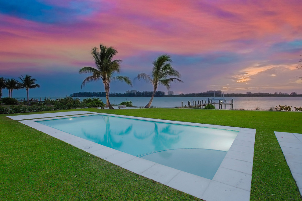 This is an example of a large tropical backyard rectangular lap pool in Tampa with concrete pavers.