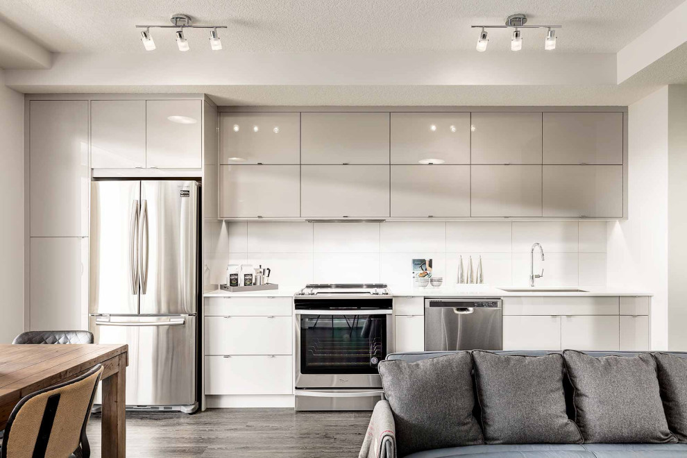 Small contemporary single-wall kitchen pantry in Calgary with an undermount sink, flat-panel cabinets, brown cabinets, quartz benchtops, white splashback, ceramic splashback, stainless steel appliances, dark hardwood floors, black floor and white benchtop.