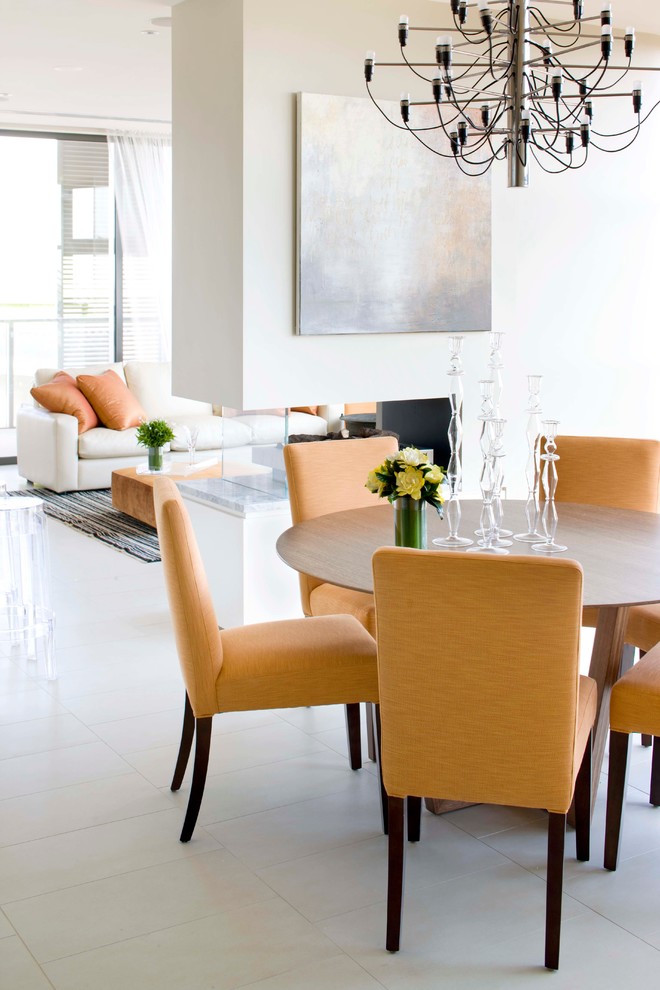 Photo of a transitional dining room in Sydney with beige walls, porcelain floors and a two-sided fireplace.