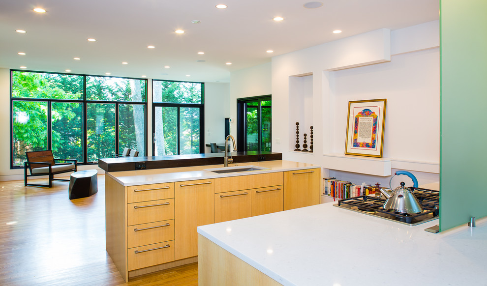 Mid-sized contemporary u-shaped open plan kitchen in DC Metro with an undermount sink, flat-panel cabinets, light wood cabinets, wood benchtops, stainless steel appliances, light hardwood floors, multiple islands, beige floor and white benchtop.
