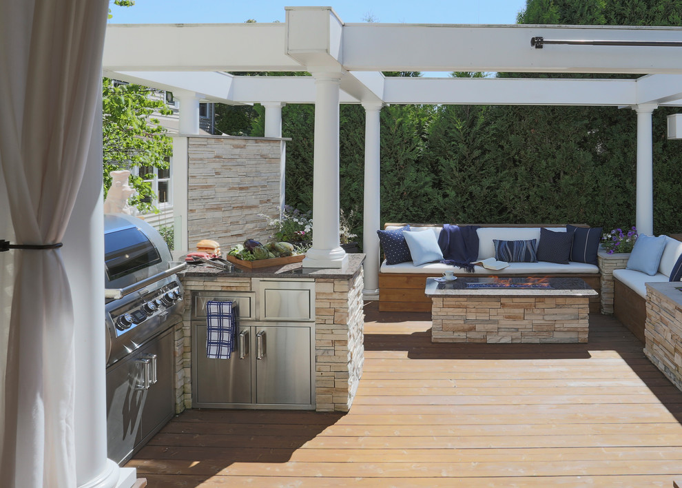 This is an example of an expansive transitional backyard deck in Chicago with an outdoor kitchen and a pergola.