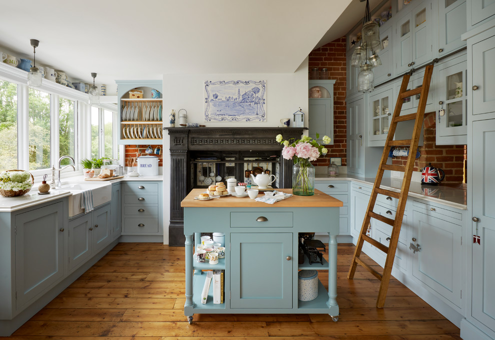 Design ideas for a large country u-shaped eat-in kitchen in Other with a farmhouse sink, shaker cabinets, blue cabinets, quartzite benchtops, medium hardwood floors, with island, red splashback, brick splashback and brown floor.