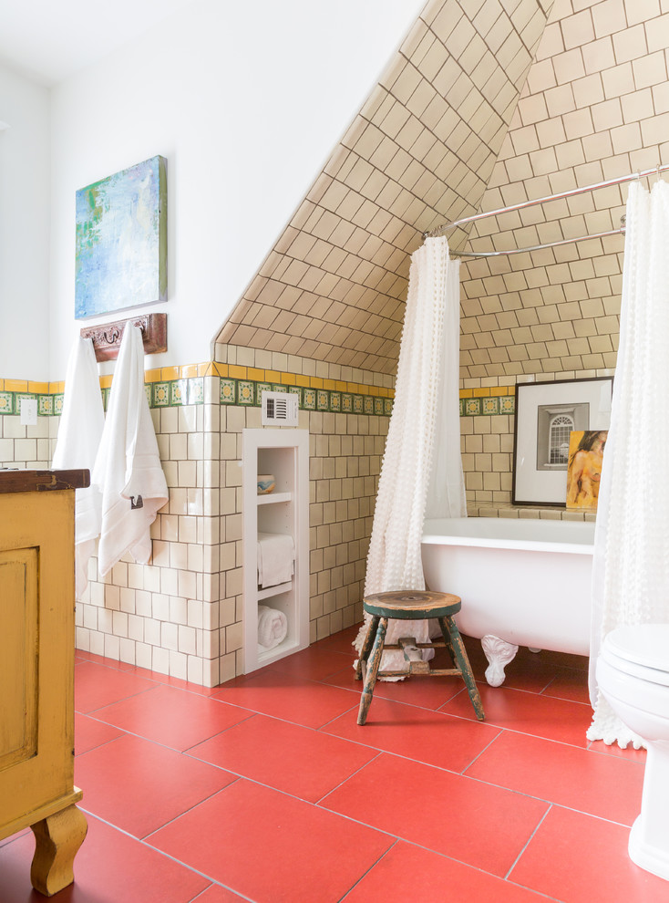 Mid-sized eclectic 3/4 bathroom in Houston with raised-panel cabinets, yellow cabinets, a freestanding tub, a shower/bathtub combo, beige tile, ceramic tile, white walls, porcelain floors, red floor and a shower curtain.