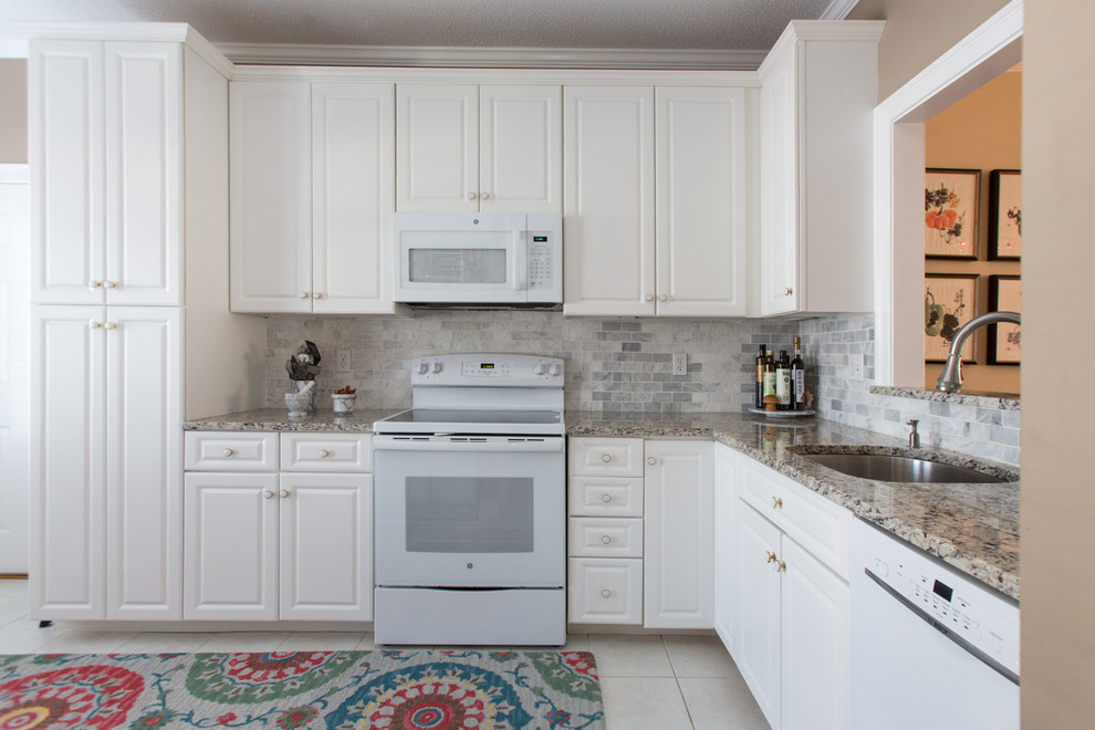 This is an example of a mid-sized transitional u-shaped eat-in kitchen in Bridgeport with a single-bowl sink, raised-panel cabinets, white cabinets, granite benchtops, grey splashback, subway tile splashback, white appliances, ceramic floors and no island.