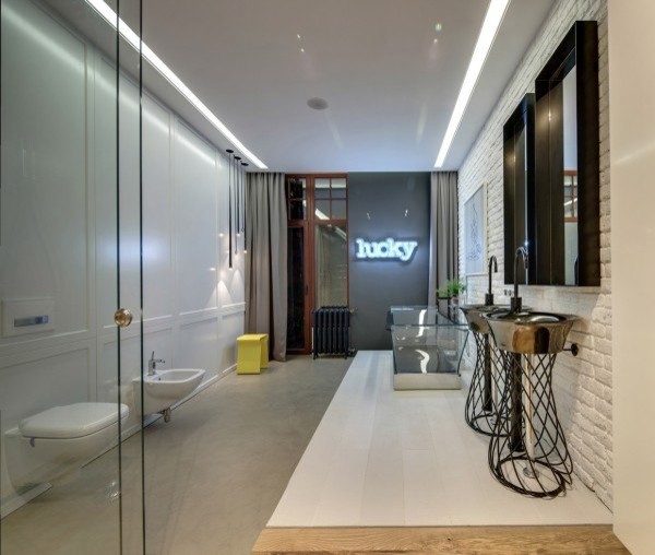 Modelo de cuarto de baño moderno con armarios tipo mueble, bañera encastrada, paredes blancas, suelo de cemento, aseo y ducha, lavabo con pedestal y encimera de madera