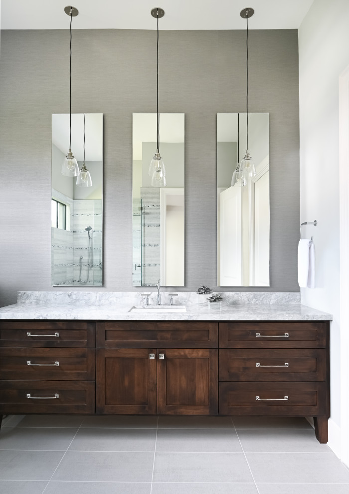 Mid-sized trendy gray tile porcelain tile, gray floor, single-sink and wallpaper bathroom photo in Houston with raised-panel cabinets, medium tone wood cabinets, gray walls, a drop-in sink, granite countertops, a hinged shower door, gray countertops and a built-in vanity