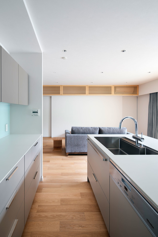 Design ideas for a small contemporary galley open plan kitchen in Osaka with a drop-in sink, beaded inset cabinets, grey cabinets, laminate benchtops, white splashback, glass tile splashback, plywood floors, with island, beige floor and white benchtop.