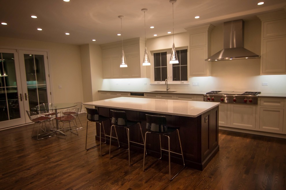 Enclosed kitchen - mid-sized transitional l-shaped dark wood floor enclosed kitchen idea in Chicago with an undermount sink, recessed-panel cabinets, white cabinets, solid surface countertops, white backsplash, porcelain backsplash, stainless steel appliances and an island