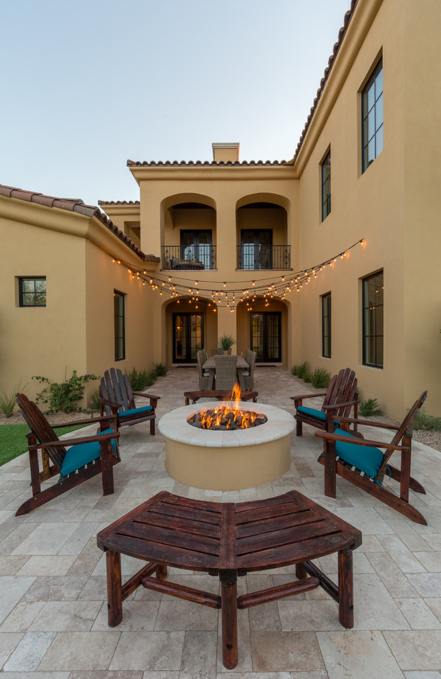 Photo of a mid-sized mediterranean courtyard patio in Phoenix with a fire feature, tile and no cover.