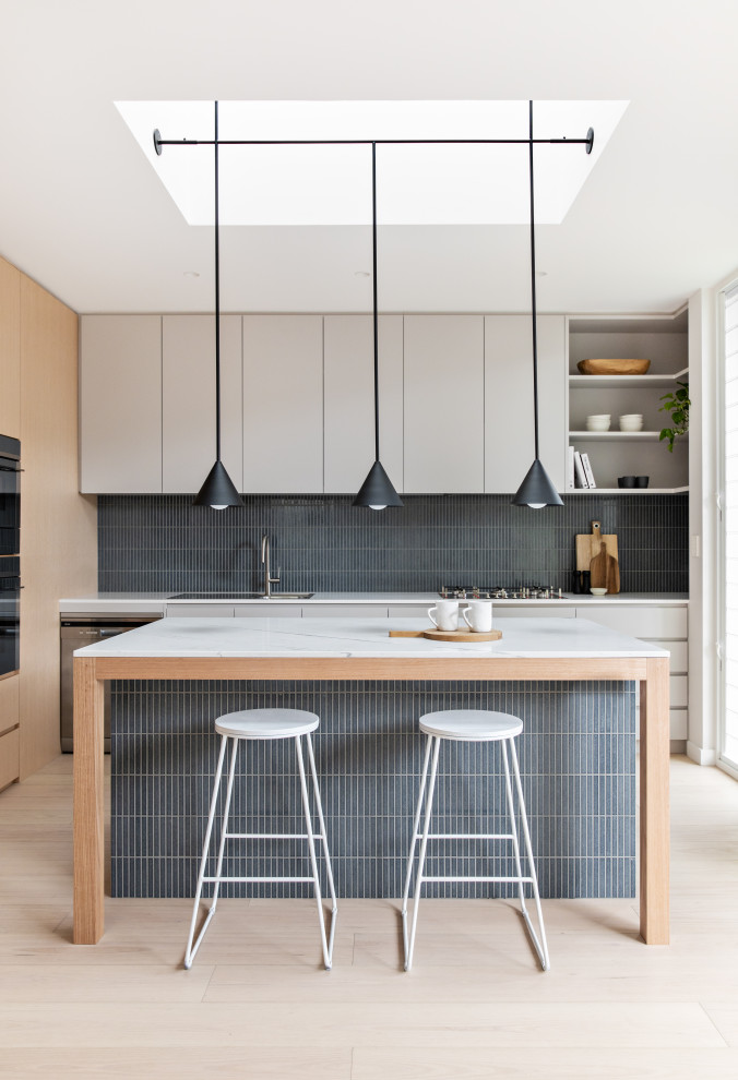 Contemporary u-shaped kitchen in Sydney with a drop-in sink, flat-panel cabinets, white cabinets, grey splashback, panelled appliances, light hardwood floors, beige floor and white benchtop.