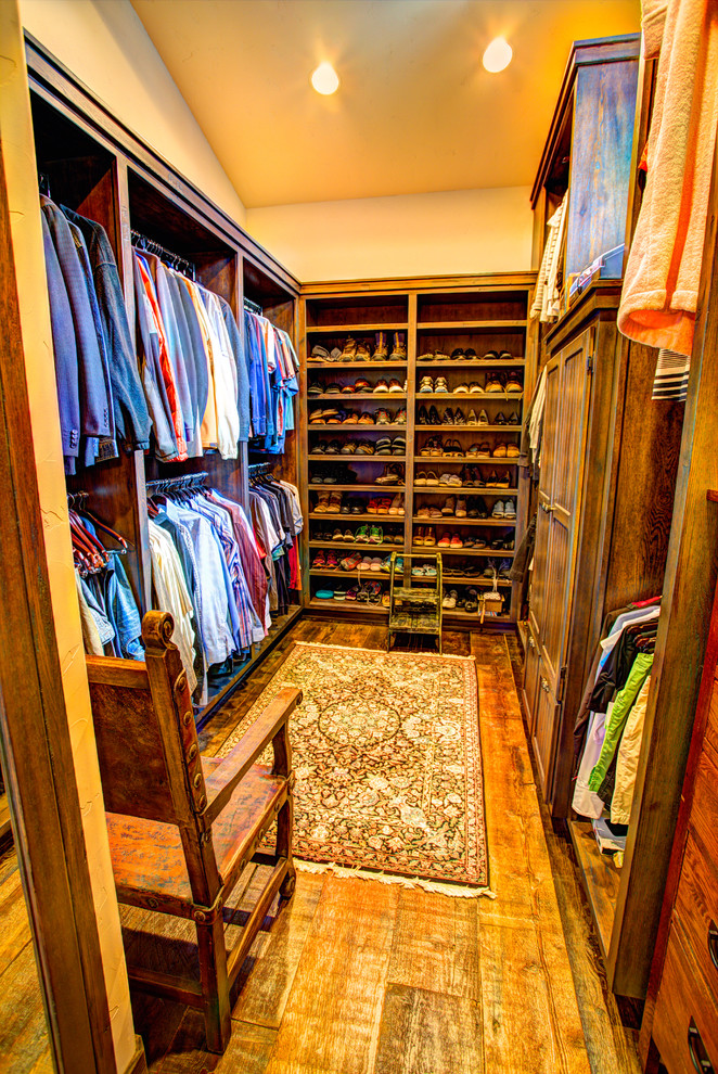 This is an example of a large country gender-neutral walk-in wardrobe in Other with flat-panel cabinets, distressed cabinets and medium hardwood floors.