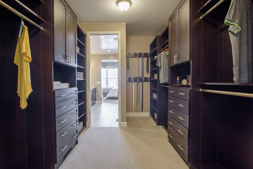 Mid-sized midcentury men's walk-in wardrobe in Denver with shaker cabinets, dark wood cabinets, carpet and beige floor.