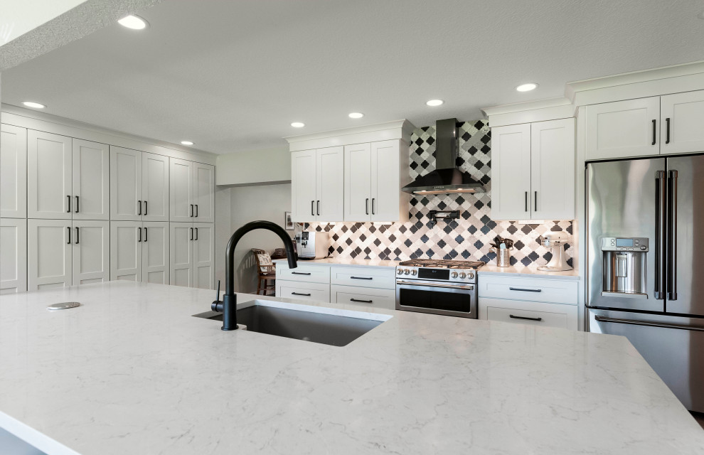 Inspiration for a large transitional vinyl floor and brown floor kitchen pantry remodel in Orlando with an undermount sink, shaker cabinets, white cabinets, quartzite countertops, multicolored backsplash, porcelain backsplash, stainless steel appliances, an island and white countertops