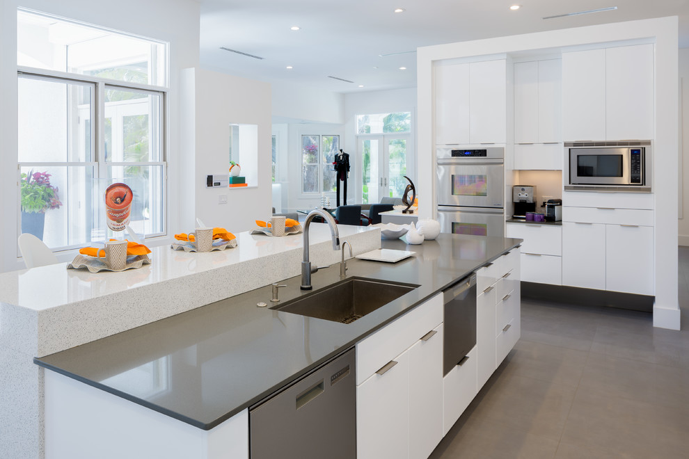 This is an example of a mid-sized contemporary open plan kitchen in Miami with flat-panel cabinets, white cabinets, metallic splashback, matchstick tile splashback, stainless steel appliances and with island.