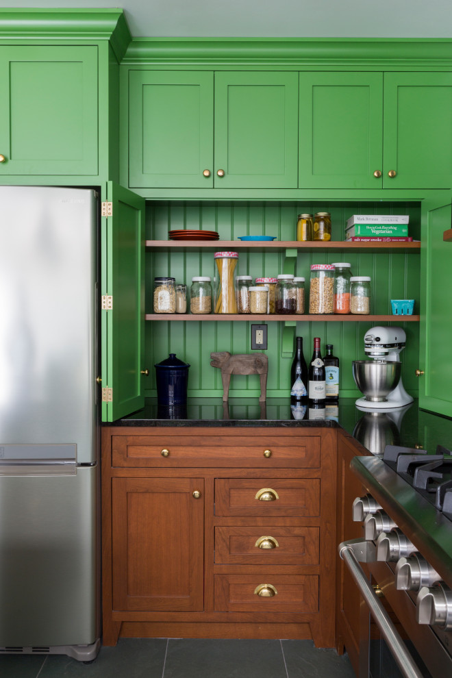 Photo of a mid-sized eclectic l-shaped eat-in kitchen in Philadelphia with an undermount sink, shaker cabinets, green cabinets, granite benchtops, white splashback, ceramic splashback, stainless steel appliances, slate floors, with island, green floor and black benchtop.