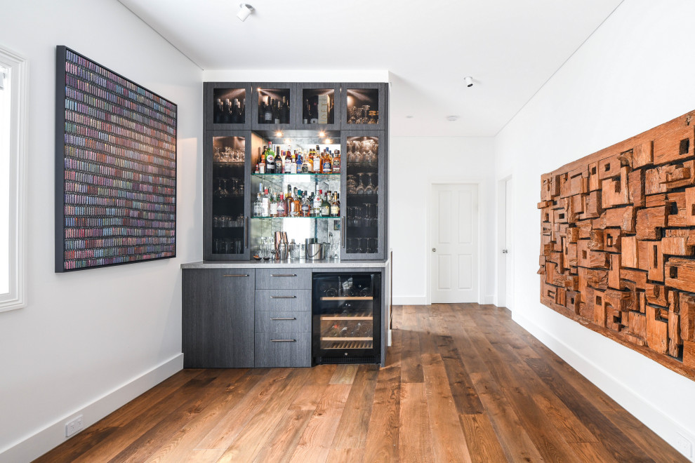 Design ideas for a small modern single-wall home bar in Sydney with no sink, flat-panel cabinets, dark wood cabinets, engineered stone countertops, grey splashback, mirror splashback and grey worktops.