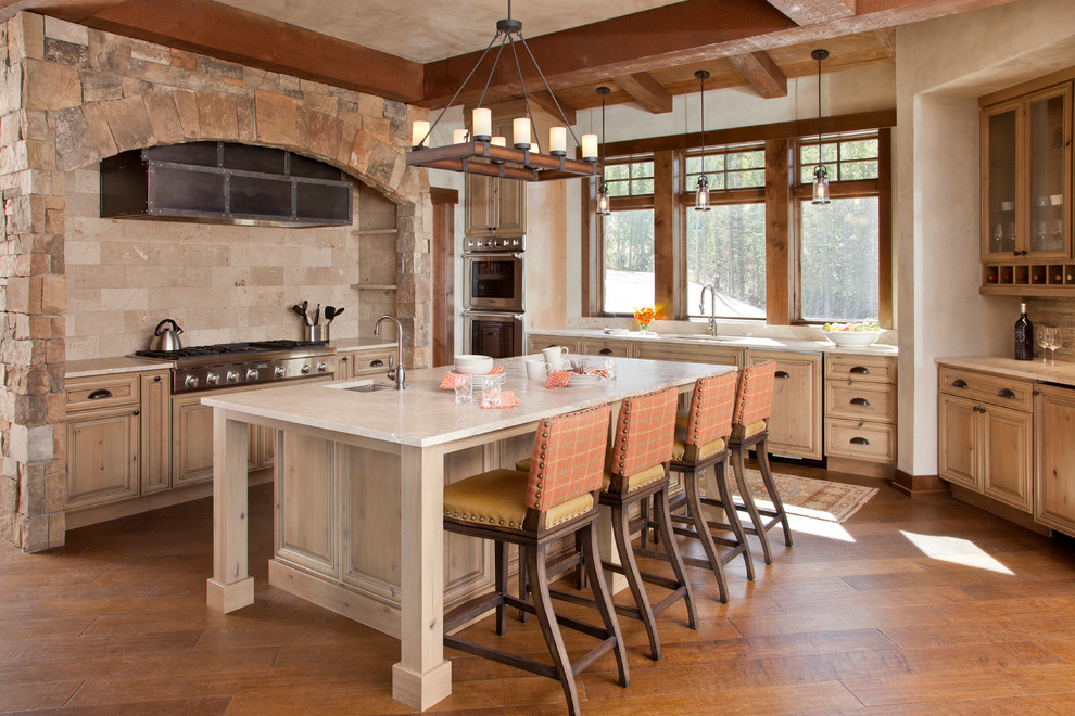Photo of a large country u-shaped eat-in kitchen in Other with an undermount sink, raised-panel cabinets, light wood cabinets, beige splashback, stone tile splashback, stainless steel appliances, medium hardwood floors, with island, quartzite benchtops, brown floor, white benchtop and exposed beam.