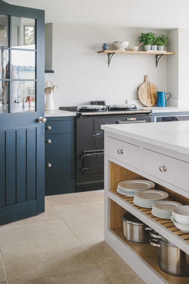 Large country l-shaped eat-in kitchen in Gloucestershire with a drop-in sink, shaker cabinets, blue cabinets, quartz benchtops, stainless steel appliances, limestone floors, with island and grey benchtop.